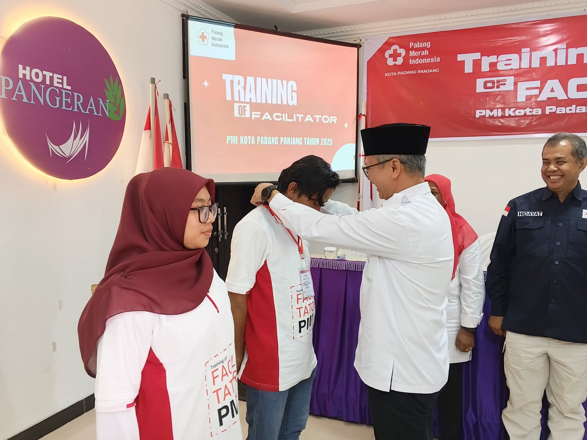 Ketua PMI Padang Panjang, Herki Toni, saat kalungkan kokarde pada salah seorang peserta pelatihan.